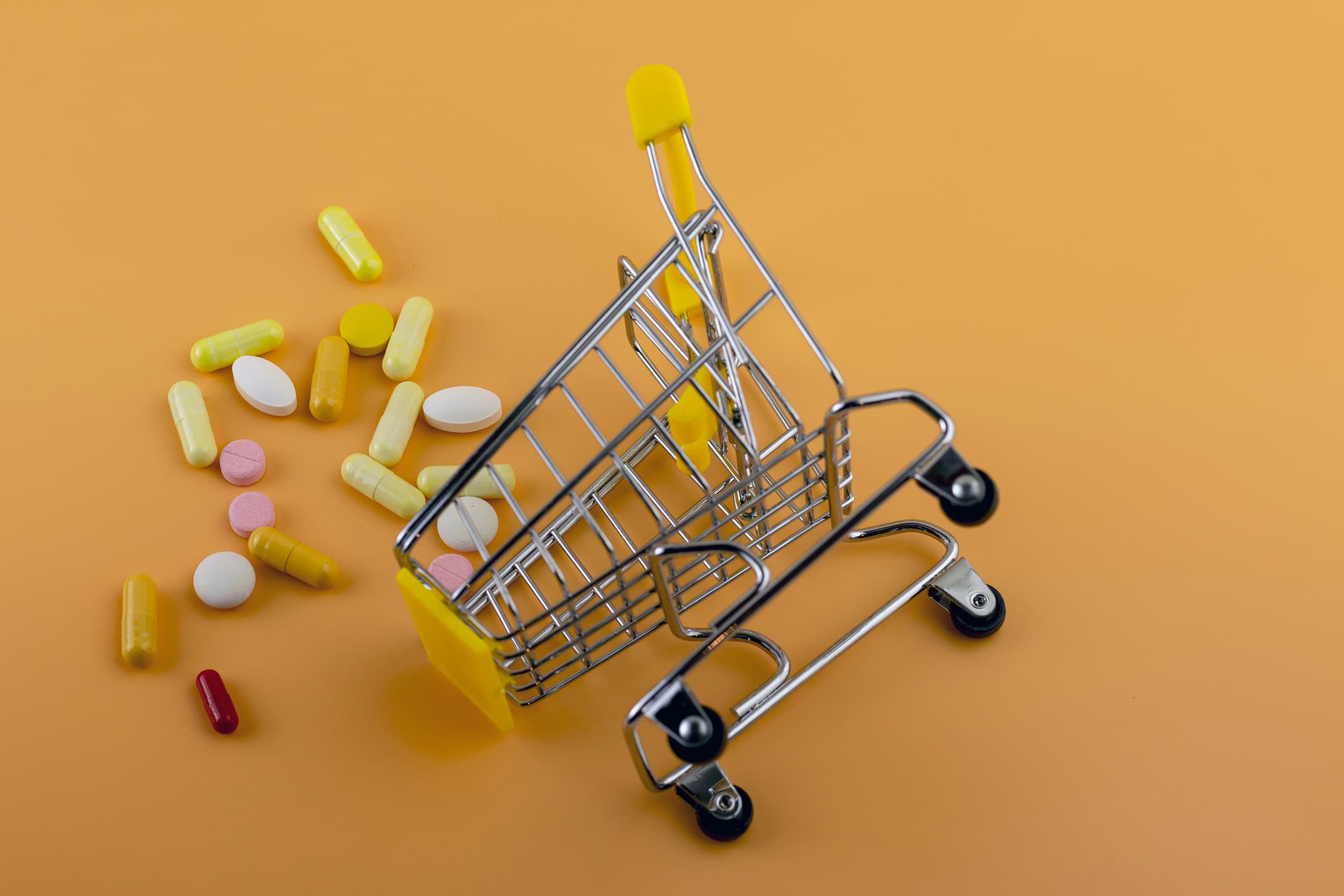 Pills, tablets and capsules of pharmaceutical medicine on a yellow background. View from above. Flat lay. Copy space. Medicine concepts. Minimalistic abstract concept. Supermarket trolley conceptual image.